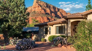 A house with a mountain backdrop, surrounded by cacti and trees. - Luxe 4-BR Home: Spa, Red Rock Views, and A+ Trails (Sedona)