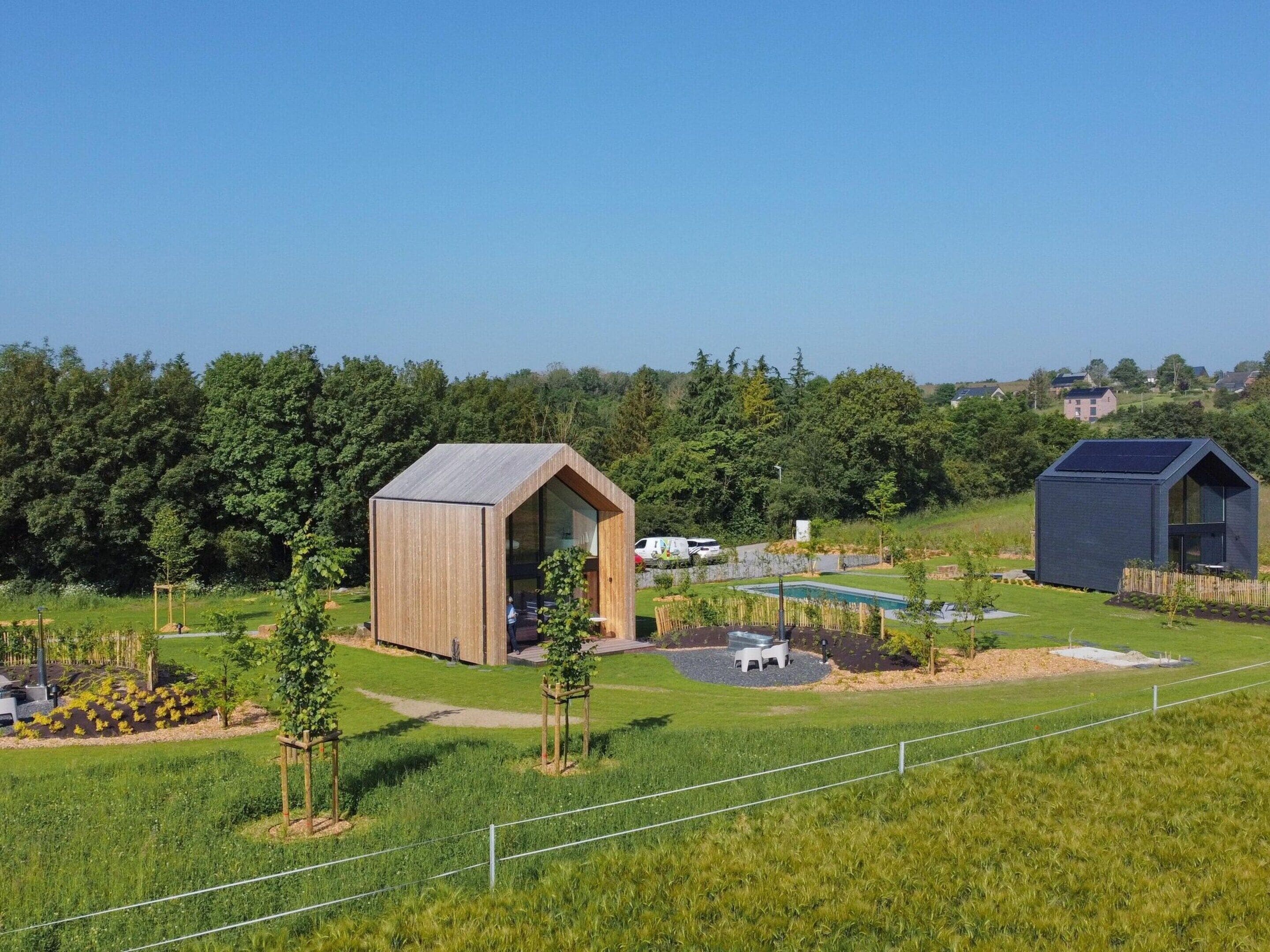 Un bâtiment moderne doté d’un toit en pente et de grandes fenêtres, entouré d’un jardin bien entretenu et d’une piscine.