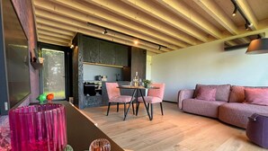 A modern interior with a wooden ceiling, a dining area with pink chairs, and a sofa with cushions. - Lodge in Durbuy With Hot Tub & Valley Views (Durbuy)