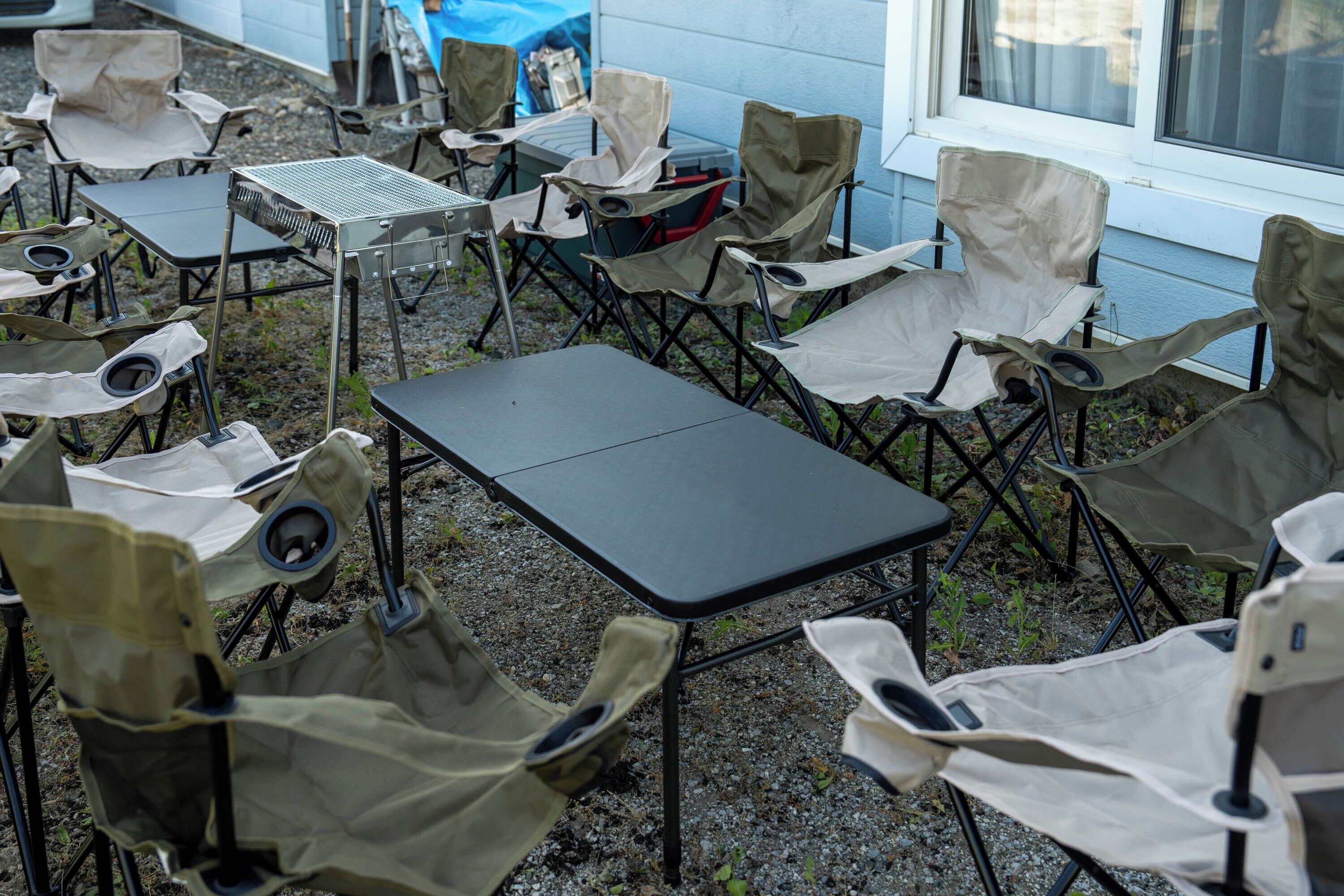 A patio area with multiple folding chairs and a table, arranged outdoors.