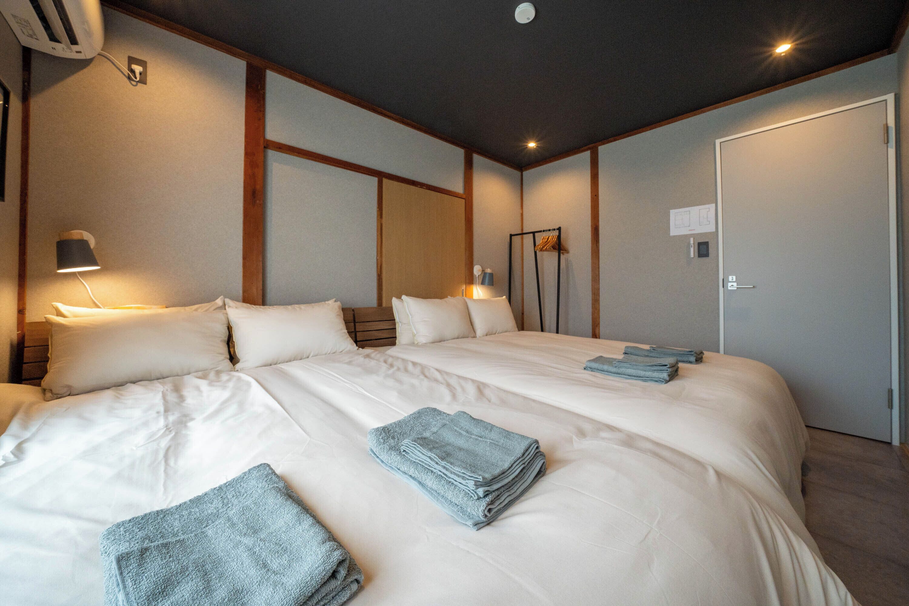 A hotel room with a large bed, a bedside table with a lamp, a wardrobe, and a door.