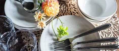 Una mesa de comedor puesta con platos, cubiertos y vasos.