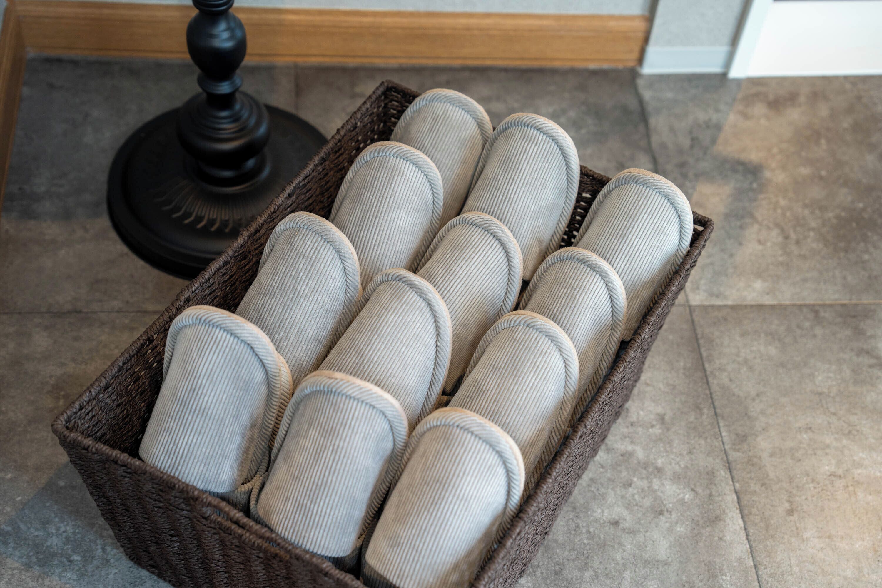 A wicker basket containing several cylindrical cushions.