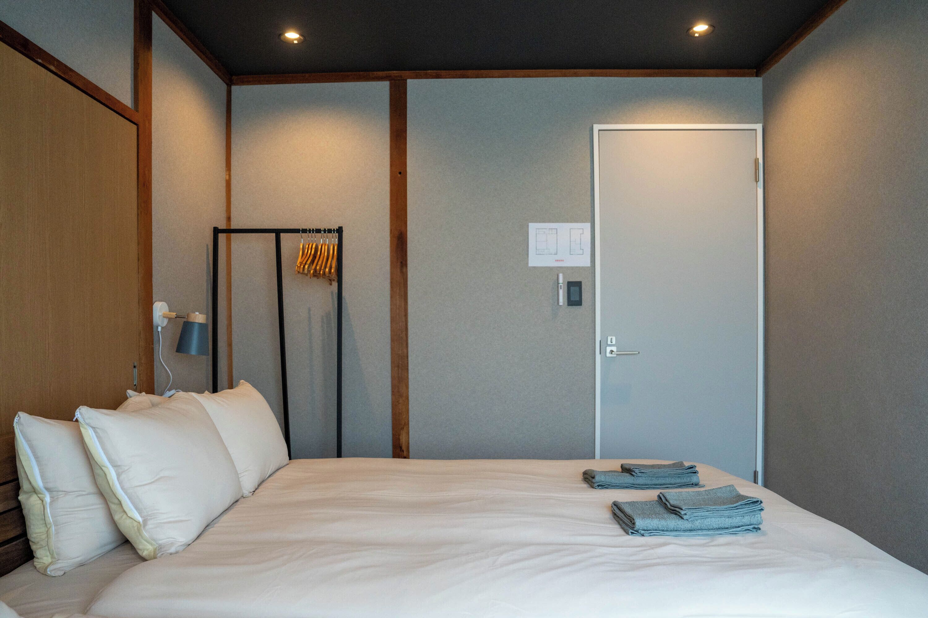Habitación de hotel con una cama grande, un armario, un perchero y una puerta con interruptor de luz.