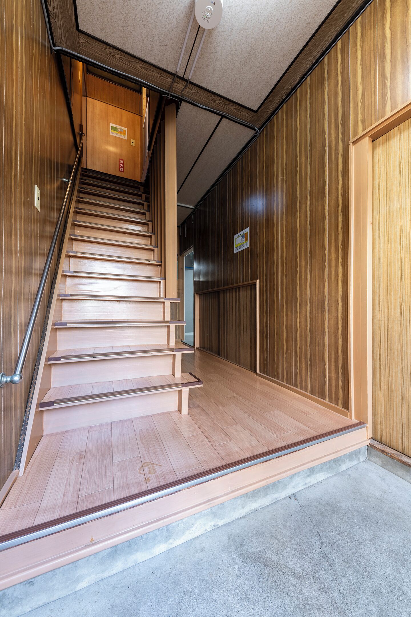 Un escalier en bois, doté d’une rampe, mène à une porte située en haut.