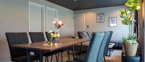 A modern dining area with a wooden table, dark chairs, and a vase of flowers.