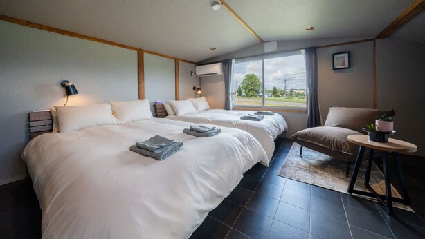 Ein Hotelzimmer mit zwei Betten, einem kleinen Tisch mit einer Pflanze und einem Fenster mit Vorhängen.