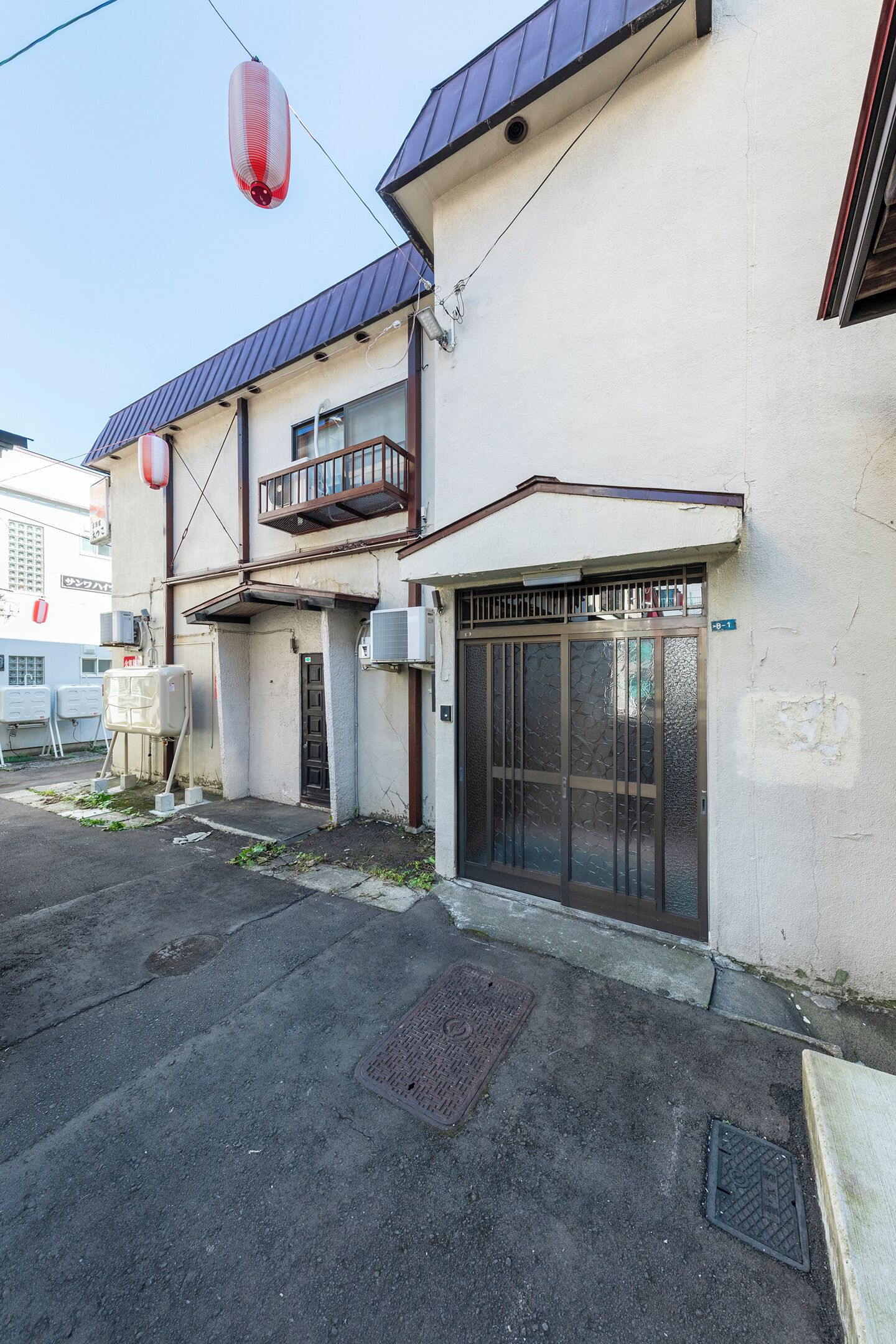 A building with a metal roof, a gated entrance, and a small balcony.