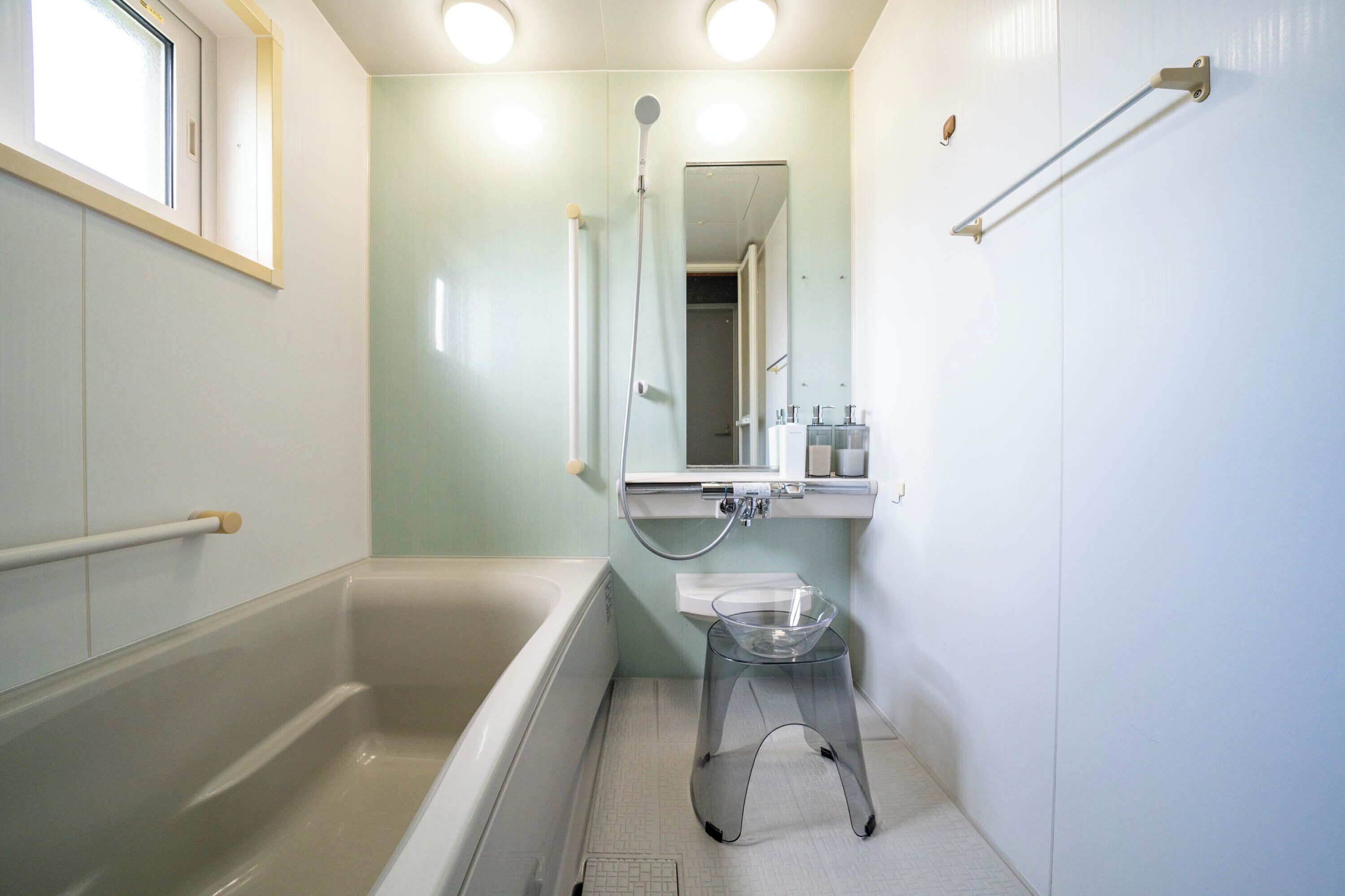 A bathroom with a bathtub, a glass stool, a shower, and a mirror.