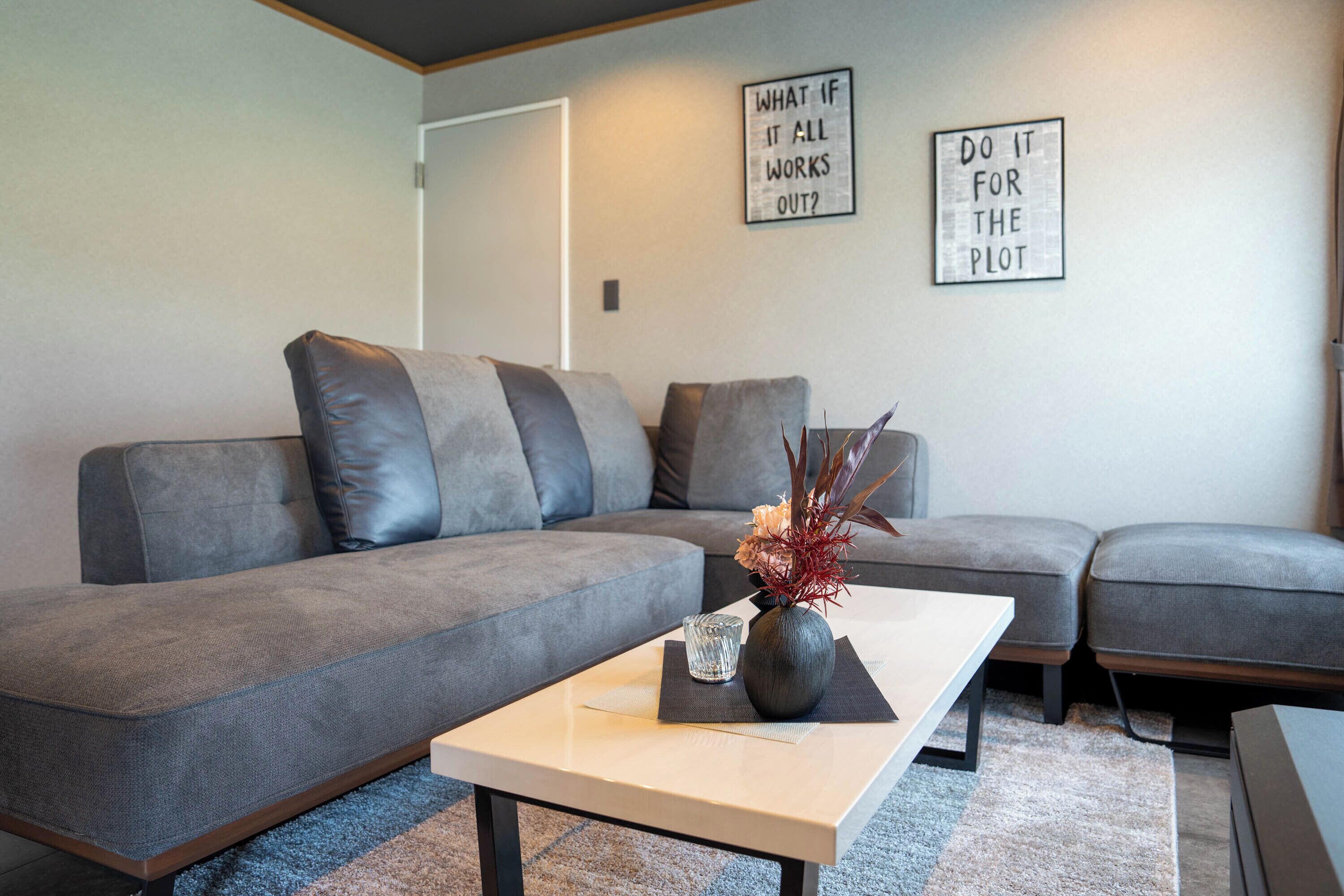 A modern living room with a grey sectional sofa, a white coffee table, and two wall art pieces.