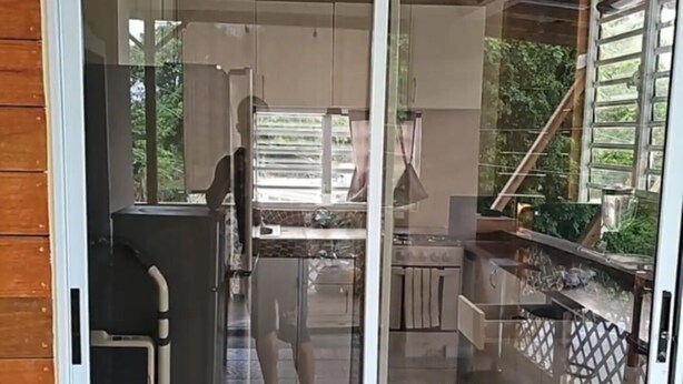 A sliding glass door leading to a kitchen with a tiled backsplash and a view of greenery outside.