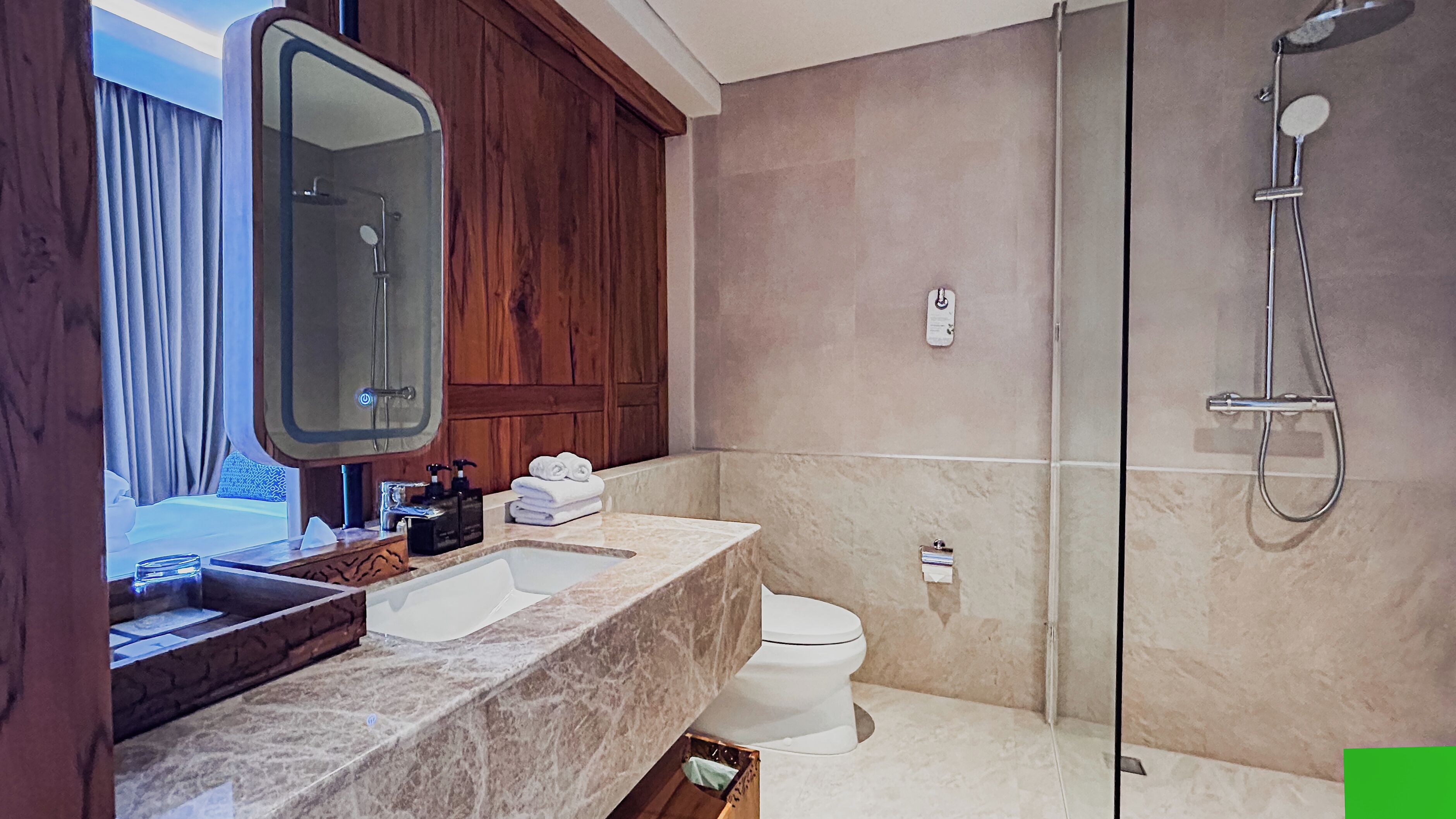 Een moderne badkamer met een marmeren wastafel, toilet en douche.