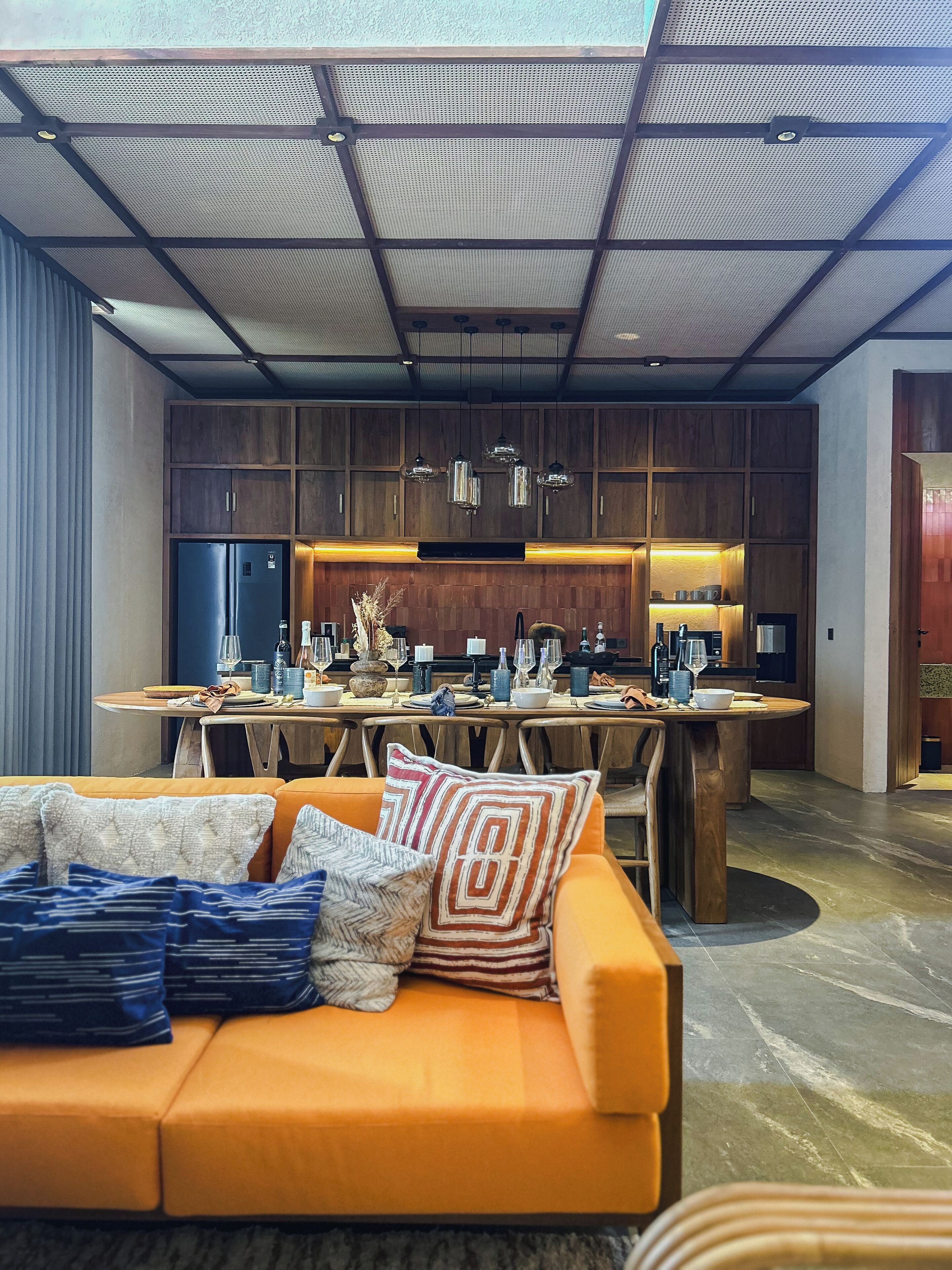A modern kitchen with wooden cabinets, a central island, and pendant lighting.
