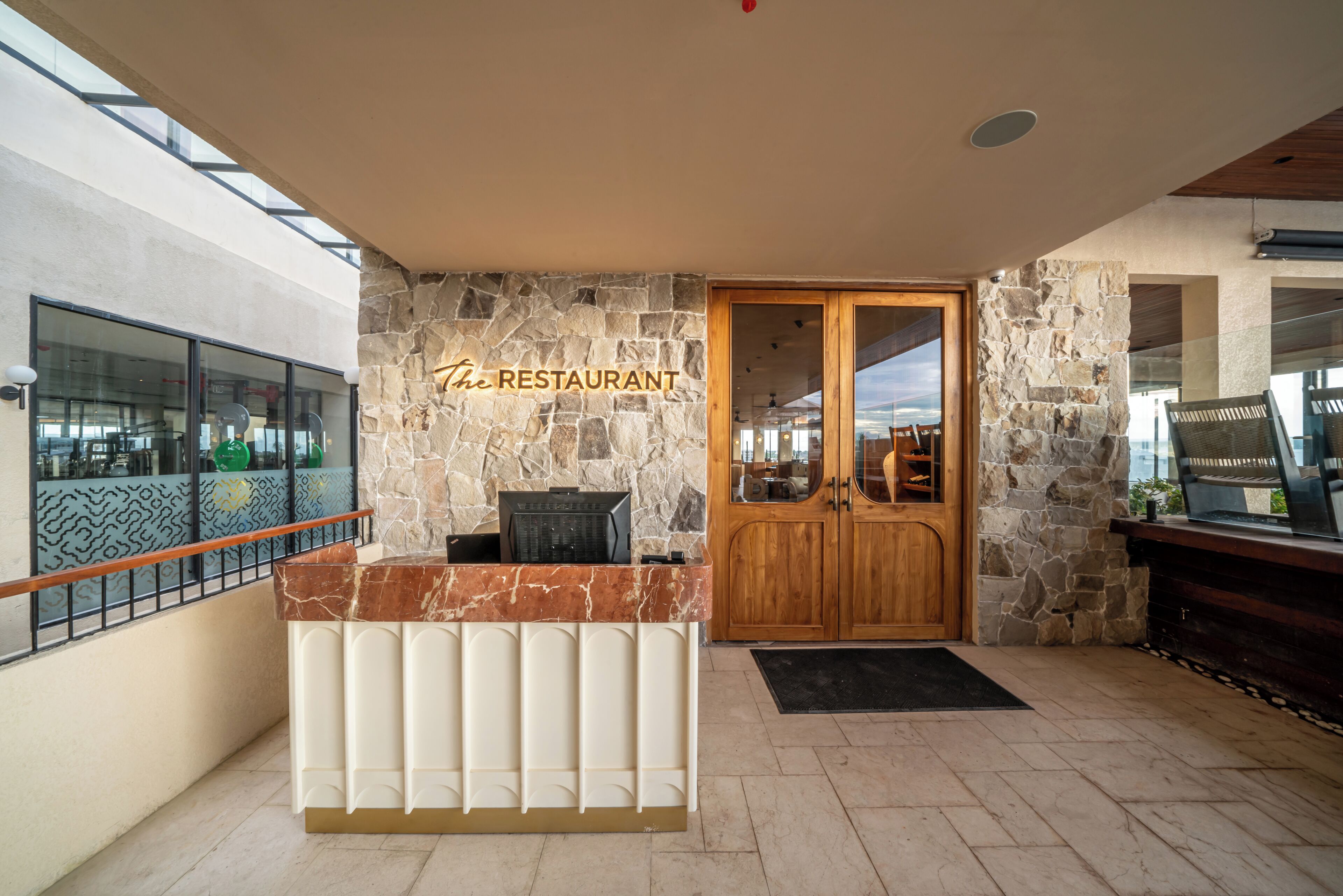 Un restaurante con fachada de piedra, una recepción de madera y una entrada de vidrio.