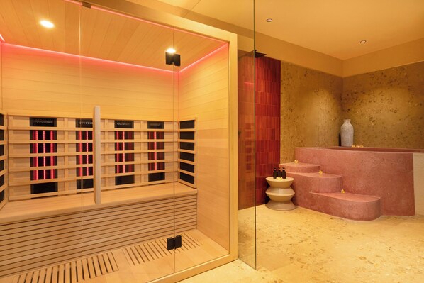 Un moderno cuarto de spa con sauna de madera, zona de ducha con cerramiento de vidrio y recepción de piedra.