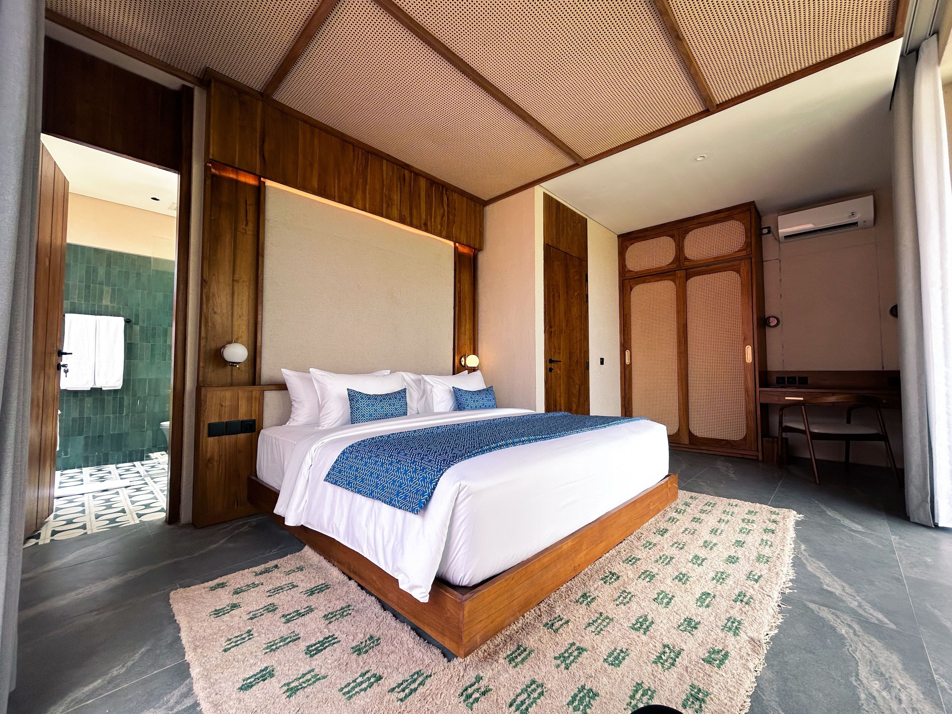 Un dormitorio moderno con una cama grande, cabecera de madera y techo con diseño perforado.