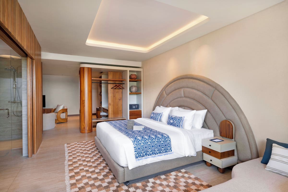 Une chambre moderne avec un grand lit, des tables de chevet, une armoire et une douche en verre.