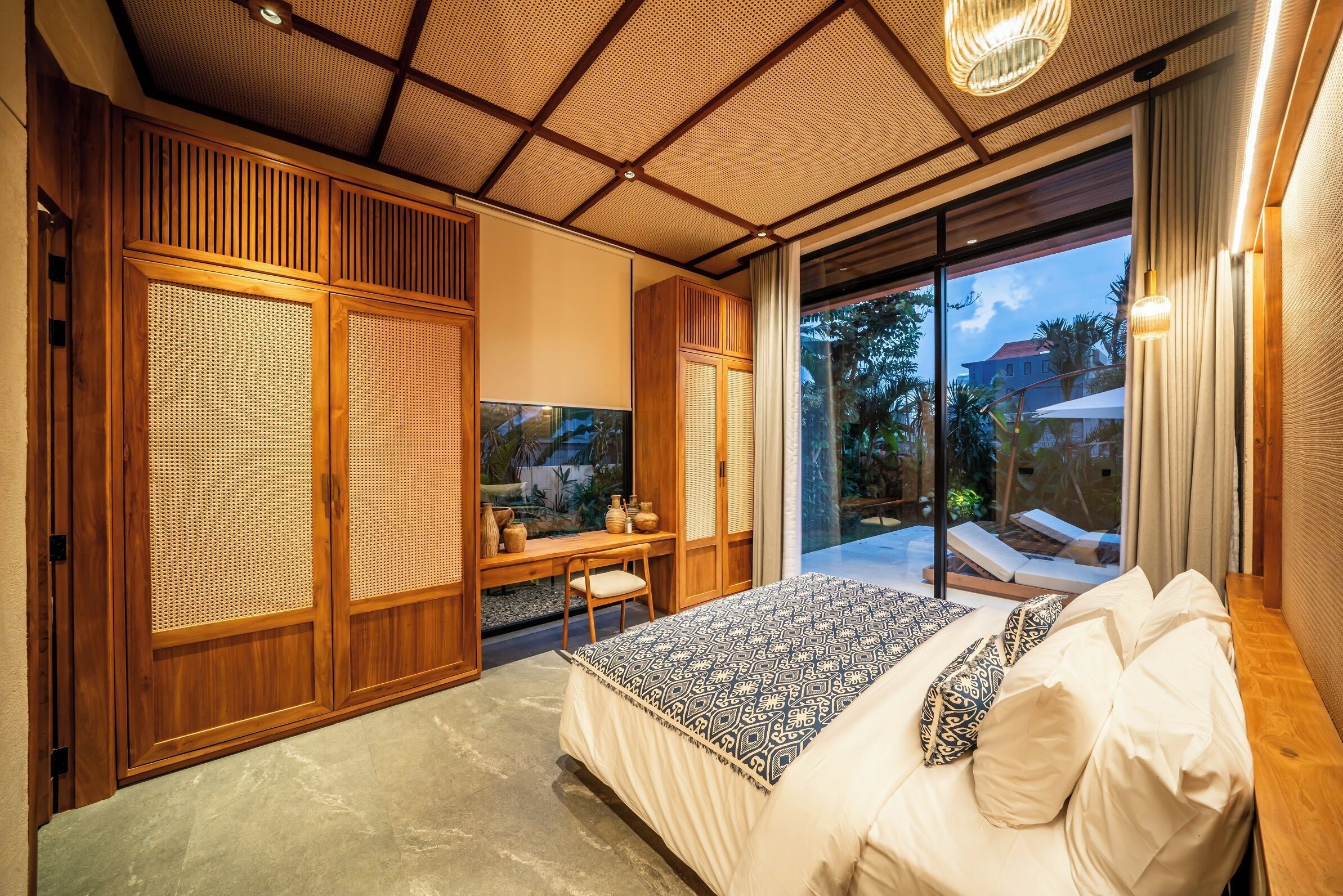 A bedroom with a large bed, wooden furniture, and a view of the outdoors.