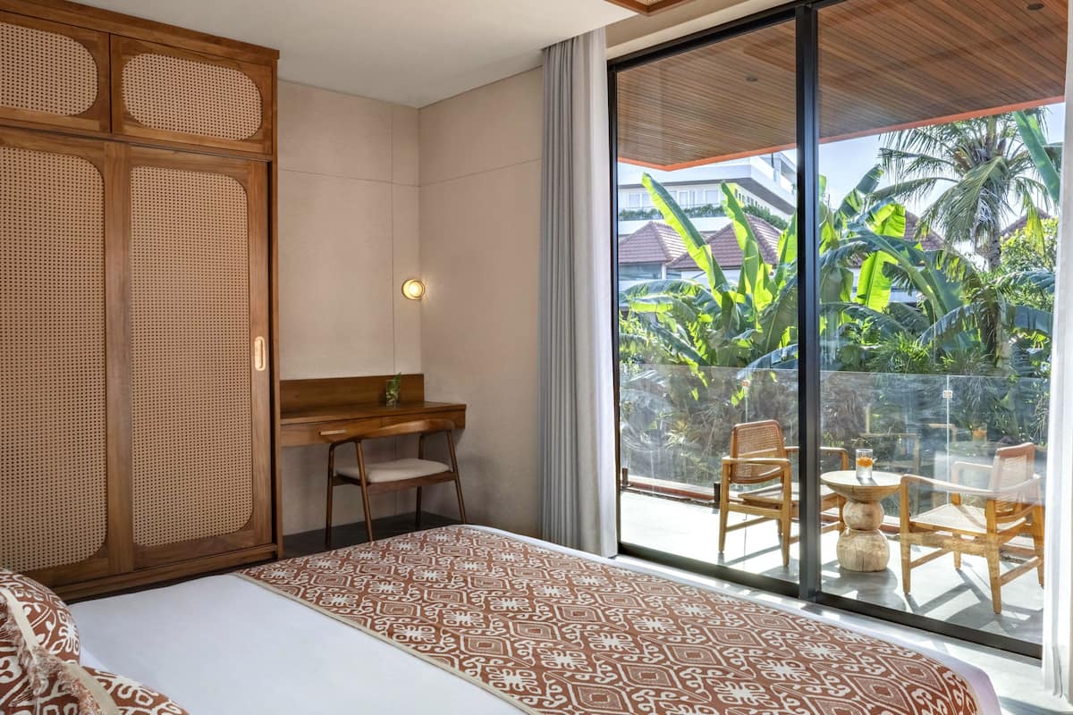 Une chambre d’hôtel avec un lit, un bureau et un balcon équipé de chaises et d’une table.