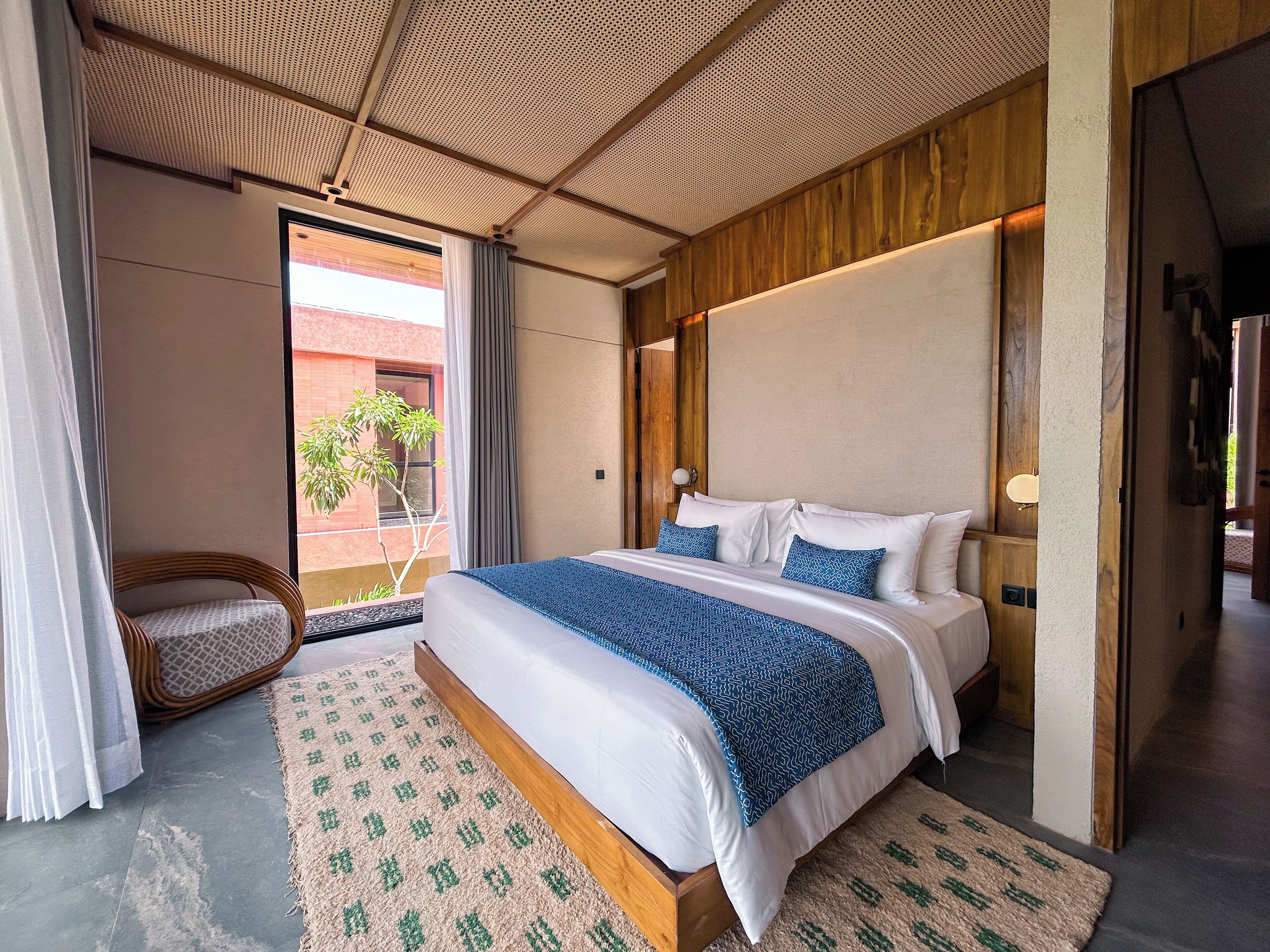 Una habitación de hotel moderna con una cama grande, un cabecero de madera y vistas al exterior.