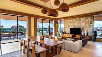 A spacious living area with a wooden dining table, comfortable seating, a stone accent wall, and a large TV.