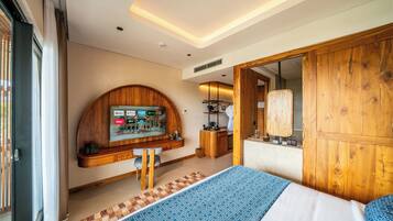 A modern bedroom with a large bed, a wooden vanity, a built-in TV, and a bathroom with a wooden door.