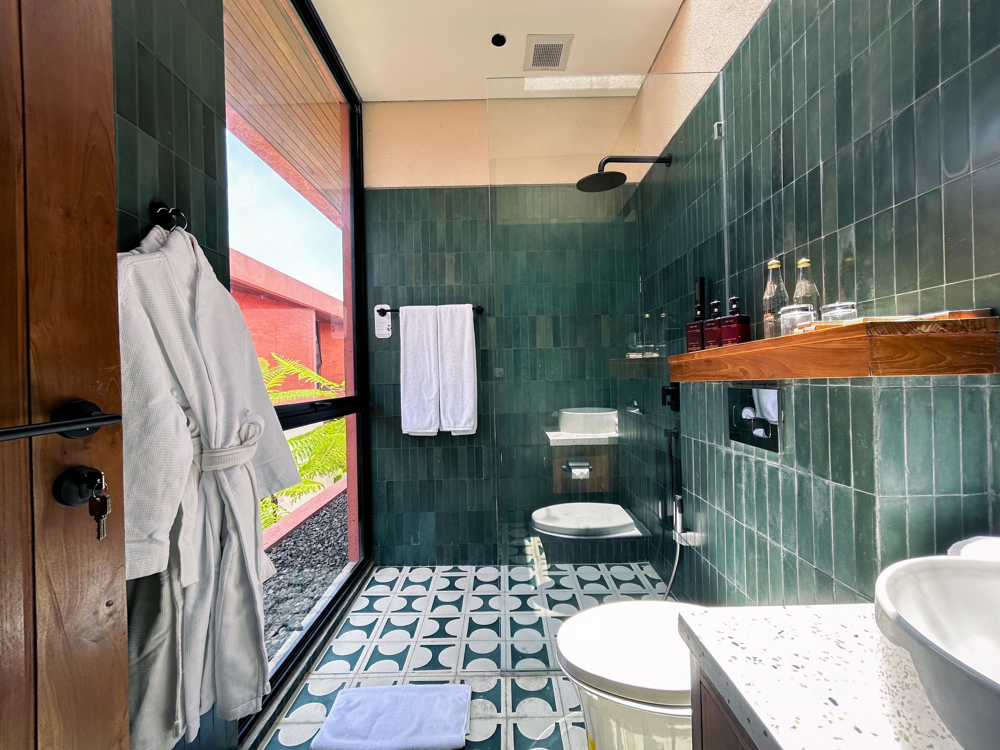 Une salle de bain moderne avec une porte en verre, une douche, des toilettes et un lavabo.