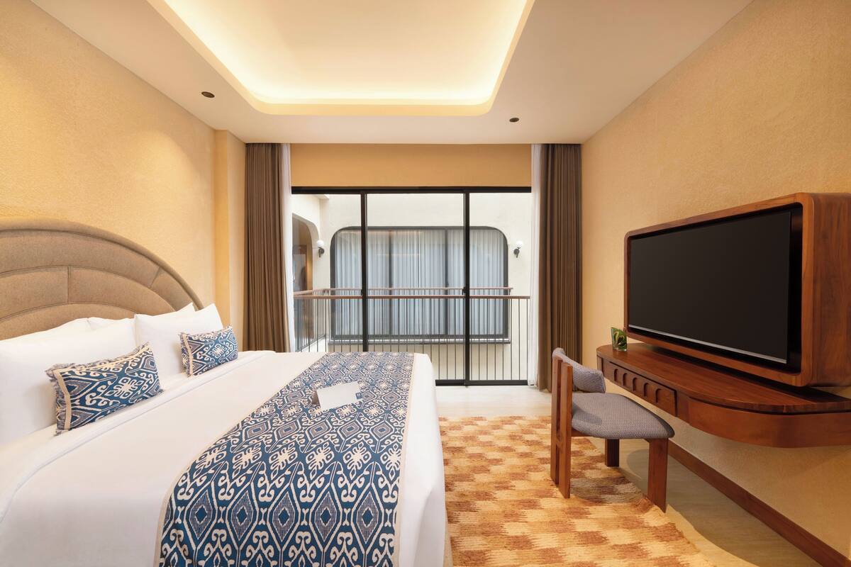 Une chambre d’hôtel avec un grand lit, une télévision, un bureau et un balcon avec vue.