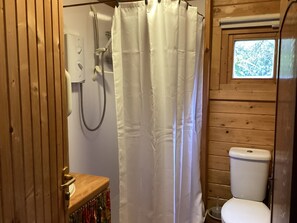A wooden bathroom with a shower curtain, a toilet, and a window. - Sleeps2- FreeWiFi - WalkersParadise - South Facing (Wells)