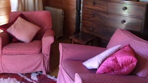A cozy room with a wooden interior, featuring a red patterned sofa, a wooden dresser, and a bookshelf. - Sleeps2- FreeWiFi - WalkersParadise - South Facing (Wells)