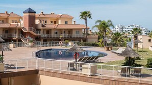 A pool area with lounge chairs, a lifeguard tower, and a palm tree.