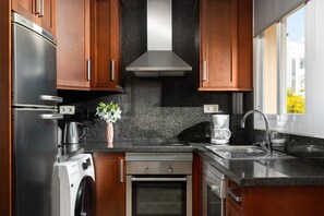 Uma cozinha moderna com eletrodomésticos de aço inoxidável, armários de madeira, bancada de granito e uma janela com vista.