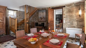 A dining area with a wooden table set for a meal, a staircase, and stone walls. - La Manoir du Moros by Interhome (Concarneau)