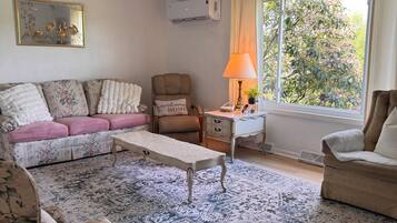 A living room with a ceiling fan, a sofa, a chair, a coffee table, and a window with curtains.