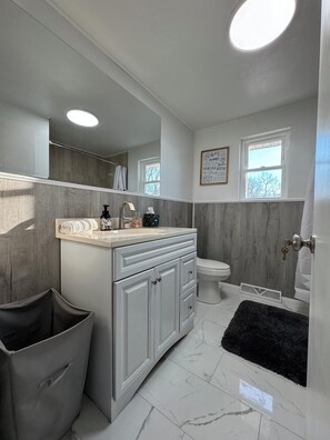 Une salle de bain moderne comprenant un meuble-lavabo, des toilettes et un espace douche.