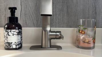 A bathroom sink with a modern faucet, a soap dispenser, and a candle.
