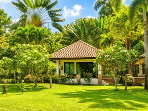 Une maison avec un toit en tuiles, entourée d’une végétation luxuriante et d’une pelouse bien entretenue.