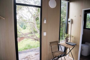 Ein Zimmer mit einer Schiebetür zum Garten, einem kleinen Tisch mit einem Laptop, einem Stuhl und einer Topfpflanze.