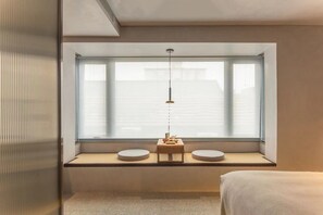 A modern room with a large window, a small table with a lamp, and a bed. - (Beijing)