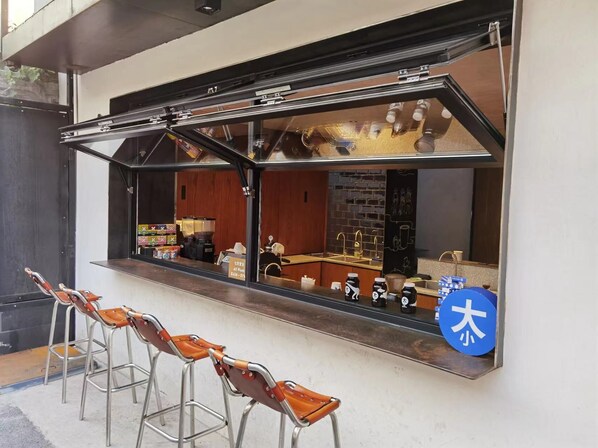 A café with a large window, metal chairs, and a blue sign with Japanese characters. - Beijing Reconstructed Space Hotel (Beijing)