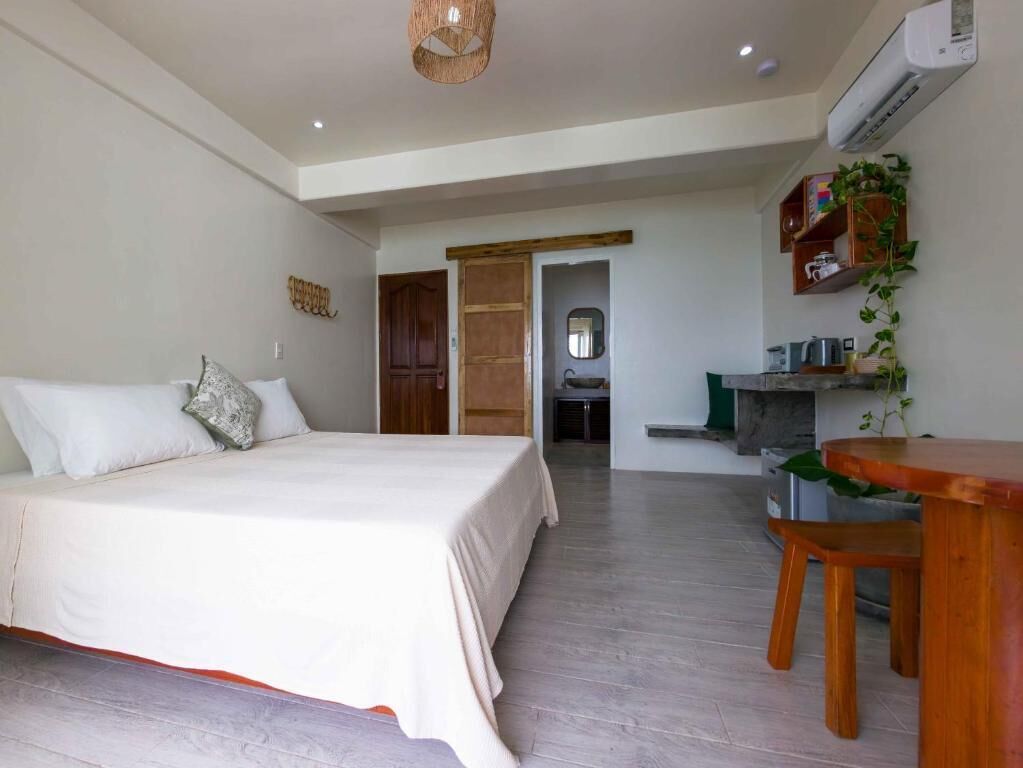 A bedroom with a bed, a wooden desk, and a chair.