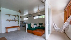 Uma sala de estar moderna com um sofá verde, mesa de centro de madeira e uma rede.