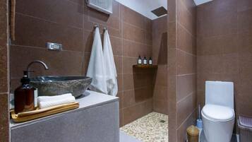 Un baño moderno con lavamanos de piedra, ducha e inodoro.