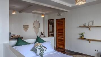 A bedroom with a bed, bedside tables, a wooden door, and a hanging light fixture.