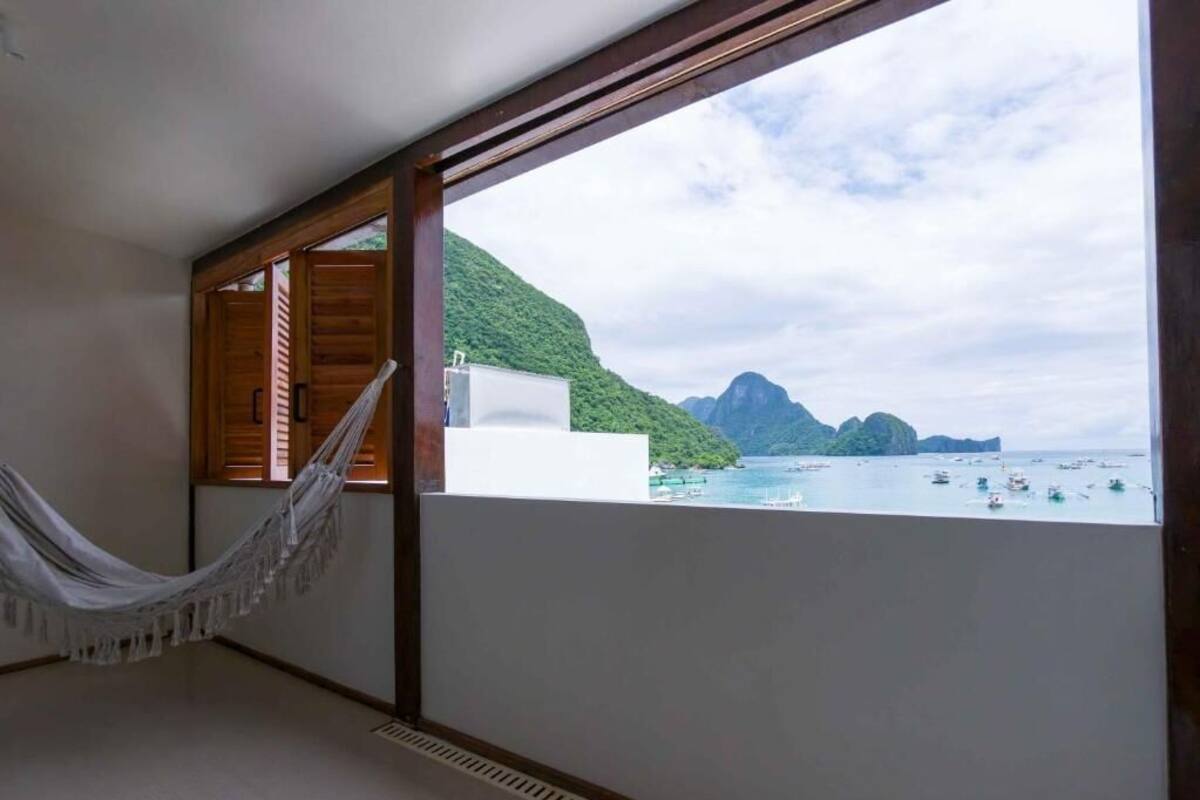 A room with a hammock, a view of the sea, and a wooden balcony.
