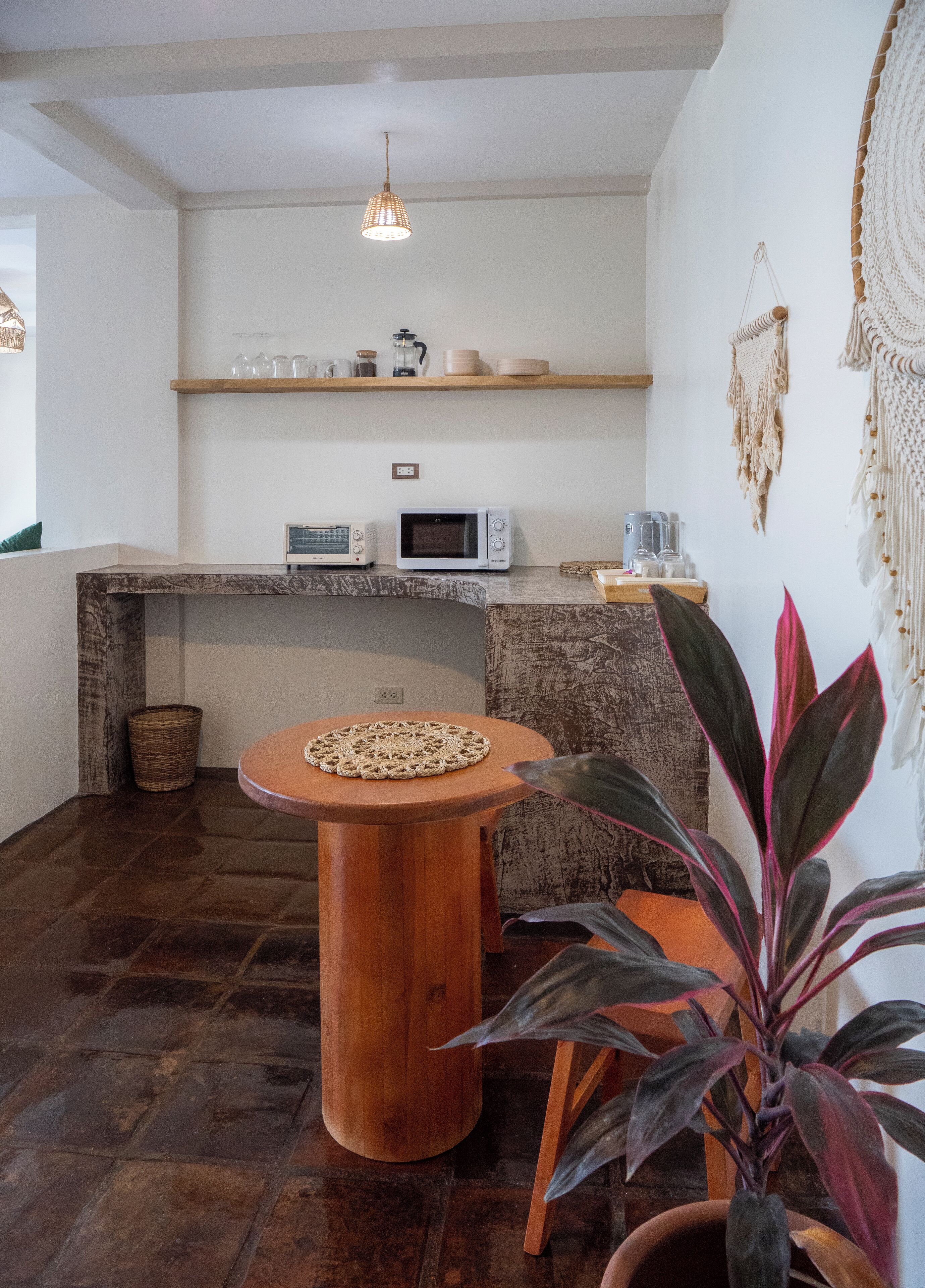 A compact kitchen with a wooden countertop, a microwave, a coffee maker, and a hanging light fixture.