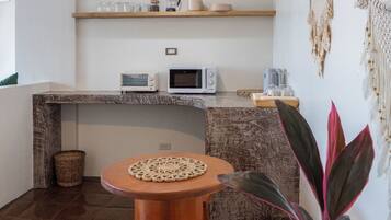 A compact kitchen with a wooden countertop, a microwave, a coffee maker, and a hanging light fixture.