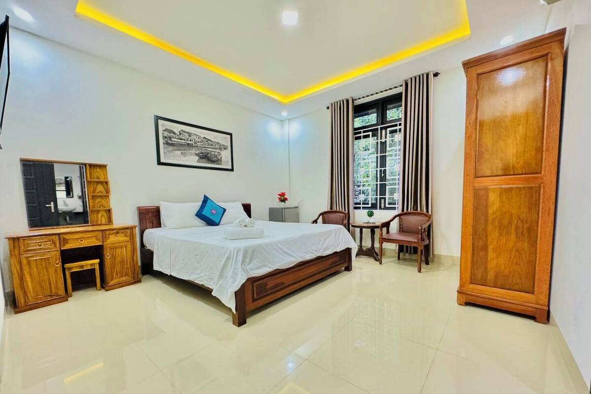A hotel room with a bed, bedside table, wardrobe, and a window with curtains.