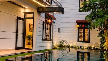 Un edificio moderno con piscina de vidrio, césped bien cuidado y diseños de ventanas tradicionales.