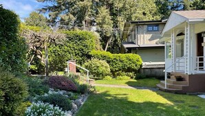 Ein Wohnhaus mit gepflegtem Garten, einer Holzdar Terrasse und einem zweigeschossigen Haus mit Veranda.
